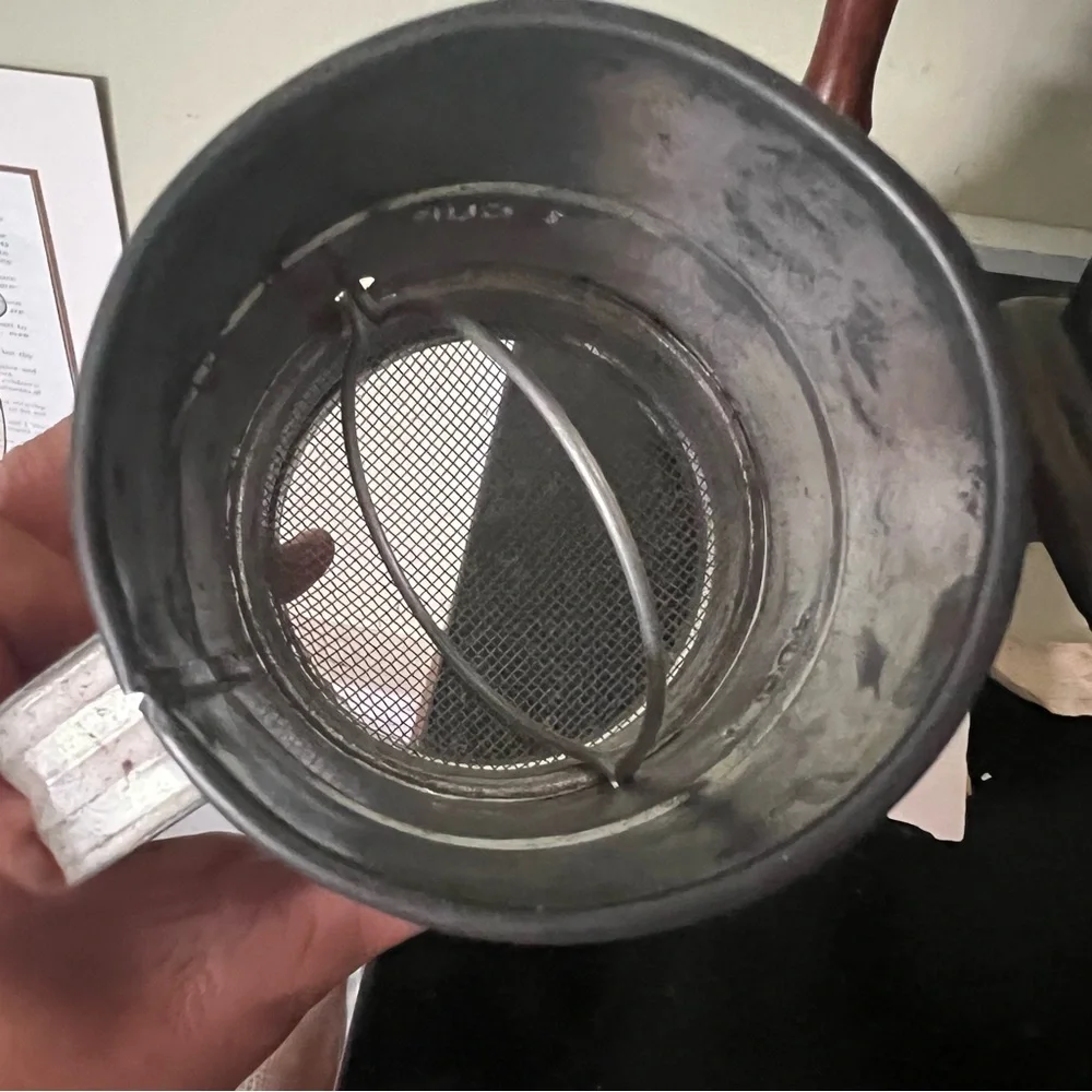 Antique, aluminum sifter with wooden handle.